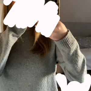 Ljusgrå stickad tröja - Mysig ljusgrå stickad tröja med rund halsringning och långa ärmar. Tröjan har ribbade muddar vid ärmslut och nederkant, perfekt för lager på lager under kyliga dagar. Super fin till alla olika outfits!