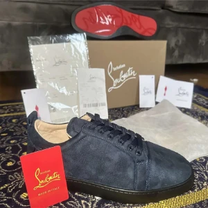 Christian Louboutin  - Exklusiva sneakers i mörkblå mocka från Christian Louboutin med klassisk röd sula. Skorna har rund tå, svarta snören och diskret branding. Perfekta för dig som vill sticka ut med stilren design och lyxig känsla.