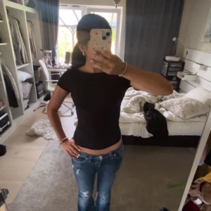 Svart croppad topp med öppen rygg - Säljer en svart, tight och croppad topp med korta ärmar. Toppen har en riktigt snygg öppen rygg som ger en cool vibe och passar perfekt till jeans. Materialet känns mjukt och stretchigt, troligen bomull eller polyester. Enkel och stilren design utan mönster.