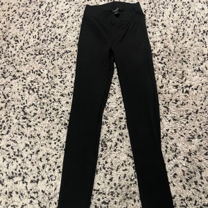 Svarta ribbade leggings från Lindex - Svarta leggings från Lindex i ribbat material. De har hög midja och är tighta i modellen, perfekta för en clean och enkel look. Stretchigt tyg som sitter skönt och följer kroppen. Passar till allt och är superenkla att styla.