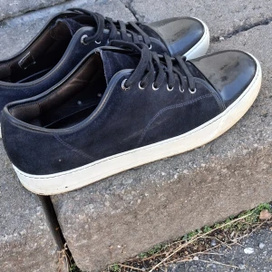 Lanvin skor navy blue. - Snygga sneakers från Lanvin i mörkblå mocka med svart lackad tå och vit sula. Klassisk låg modell med snörning och rund tå. Perfekta för dig som vill ha en stilren men ändå unik look. 