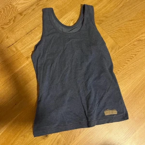 Mörkgrå vintage linnetopp från Paul Simon - En stilren vintage retro mörkgrå linnetopp från Paul Simon med klassisk rund halsringning. Toppen är ärmlös och har en enkel, rak passform. Perfekt för varma dagar eller som lager under skjorta eller jacka.