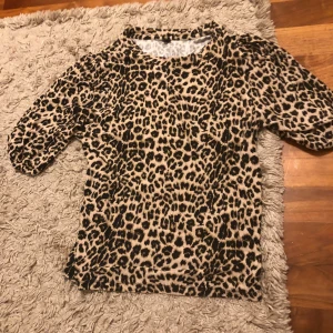 Leopardmönstrad topp  - Säljer en snygg topp i leopardmönster med beige och svarta toner. Modellen har trekvartsärm med puffiga ärmar och rund halsringning. Perfekt för dig som vill sticka ut med ett djurmönstrat plagg. Materialet känns mjukt och följsamt mot huden💗💗Köpt för 200kr