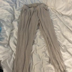 Beige ribbade mjukisbyxor från Lindex - Säljer ett par beige ribbade mjukisbyxor från Lindex i storlek 158/164. Byxorna har elastisk midja och är gjorda i mjukt stickat material som är superbekvämt. Perfekta för chill dagar hemma eller när du vill ha en avslappnad stil.