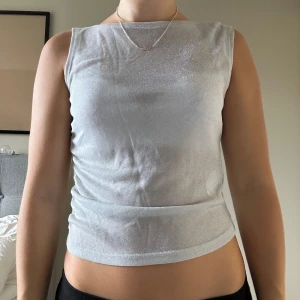 Silvertopp  - Silvrig topp, som är lite indragna detaljer i midjan. Knappt använd, så i jättebra skick. Tryck inte på KÖP DIREKT utan skriv privat om du är intresserad! 💛