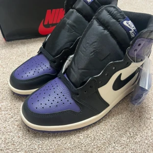 Nike Air Jordan 1 Court Purple High - *SVARTA🖤 OCH LILA💜SKOSNÖREN FÖLJER MED*😍😍😍Nike Air Jordan 1 High i färgen Court Purple med svart, vitt och lila läder. Klassisk siluett med svart swoosh, perforerad tåbox och högt skaft. Kommer med extra lila skosnören och ikonisk Nike Air-logga på plösen. Perfekta för dig som vill sticka ut med stil.