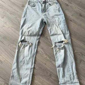 Ljusblå slitna jeans - Ljusblå jeans med raka ben och stora slitningar över knäna för en cool, avslappnad look. . Perfekta för dig som gillar vintagevibbar och streetstyle. Oanvända 