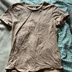 Beige basic t-shirt  - Enkel beige t-shirt i mjuk bomull med rund hals och korta ärmar. Perfekt för en avslappnad stil och lätt att matcha med andra plagg. Klassisk passform och neutral färg som funkar året runt.