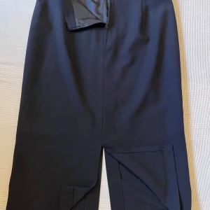 Svarta kostymbyxor från Gerry Weber - Stilrena svarta kostymbyxor från Gerry Weber i storlek 44. Byxorna har rak passform, diskret dragkedja i sidan och är tillverkade i ett mjukt, vävt material som ger en dressad look. Perfekta för dig som gillar klassisk och enkel stil.