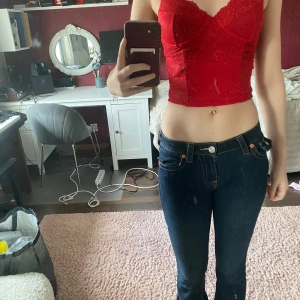 Röd spetskorsett från NA-KD - Säljer en röd croppad korsett från NA-KD i spets med v-ringad byst och tunna axelband. Toppen har fina spetsdetaljer och en figurnära passform som framhäver midjan. Knappt använd. 