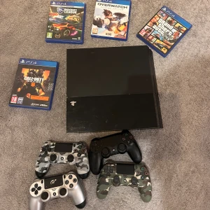 PlayStation 4 med 4 handkontroller och 4 spel - Sony PlayStation 4 i bra skick, med fyra DualShock 4-kontroller (varierande färger/designs)( någon kanske inte funkar) och populära spel: Rocket League, Overwatch, GTA V och Call of Duty Black Ops 4. Konsolen och tillbehören ser välskötta ut, inga synliga större repor eller skador. 