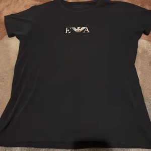  Armani t-shirt - Mörkblå t-shirt med klassisk passform från Emporio armani. T-shirten har rund hals och korta ärmar, perfekt för en clean och stilren look.