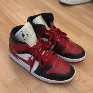 Nike Air Jordan 1 Chicago sneakers - Säljer ett par klassiska Nike Air Jordan 1 Chicago i rött, svart och vitt skinn. Ikonisk high-top siluett med röda snören, svart swoosh och vit plös med Jumpman-logga. Perfekta för dig som vill sticka ut med en tidlös sneakerlegend.