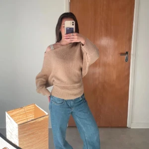 Beige stickad offshoulder-tröja NA-KD - Säljer en beige stickad tröja från NA-KD i offshoulder-modell. Tröjan har bred mudd i midjan och är vida i ärmarna, vilket ger en snygg och avslappnad passform. 