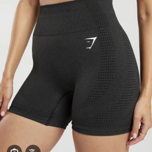 Svarta seamless shorts från Gymshark - Säljer ett par svarta seamless shorts från Gymshark med hög midja och diskret hålmönster längs sidorna. Stretchigt material som sitter tight och bekvämt, perfekt för träning. Gymshark-logga i vitt framtill. Riktigt snygga och trendiga shorts! Det finns flera färger kolla min profil 😉. Nypris ca 500kr.
