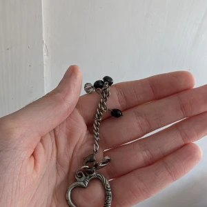 Mix av smycken: hjärtnyckelskedja/hänge & örhängen - Paket med tre smycken: ett silverfärgat hjärtskedja/hänge med hjärthänge och svarta pärlor, ett par örhängen med stora blå stenar i silverfärgad infattning samt ett par små örhängen formade som regnbågsfärgade delfiner. Perfekt för dig som gillar unika accessoarer. Skriv för fler bilder.