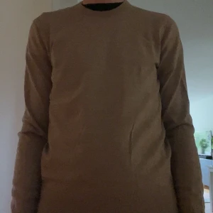 Beige stickad tröja från Uniqlo - En enkel och snygg beige stickad tröja från Uniqlo med rund hals och långa ärmar. Tröjan har en clean look utan detaljer och är perfekt för dig som gillar stilrena plagg. Mjuk och skön passform som funkar till många olika outfits. 