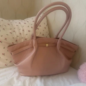Ljusrosa handväska i skinn - Säljer en ljusrosa handväska med två rejäla handtag och stilren design. 