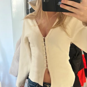 Beige v-ringad kofta med knappar - Säljer en beige v-ringad blus med långa ärmar och snygga knappar framtill. 