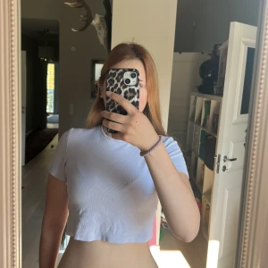 Ljuslila croppad ribbad topp - Enkel och stilren ljuslila croppad topp med korta ärmar och rund hals. Toppen är ribbad och har en tight passform som framhäver figuren. Perfekt att matcha med jeans eller kjol för en trendig look. Färgen är mer lik de första bilderna.