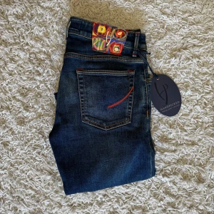 Handpicked Orvieto jeans - Snygga mörkblå jeans från Handpicked med röda detaljer. Slimfit storlek 31. I ny skick.