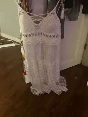 Vit långklänning med spets och snörning - Superfin vit långklänning med spetsdetaljer och smala axelband. Klänningen har snygg snörning framtill, virkade partier upptill och vackert spetsmönster hela vägen ner. Använd 2-3 gånger, köpt på marknad i Spanien! Köpt för ca 400 kr?