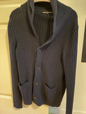 Mörkgrå ribbad kofta från dylan - Säljer en mörkgrå stilren cardigan. Koftan har bred krage, fyra knappar framtill och två praktiska fickor. 