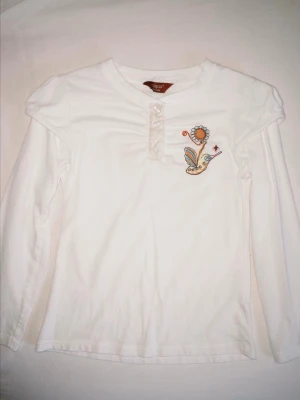 Vit långärmad topp från Guess - Jättesöt vit långärmad topp från märket Guess i bomull. Perfekt till våren  Uppskattar storlek till ca 116-134, barnstorlek