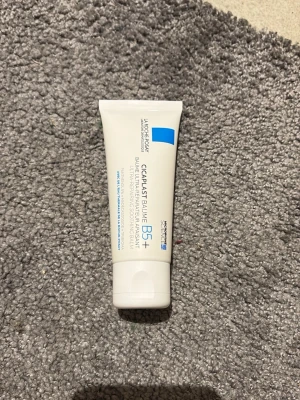 La Roche-Posay Cicaplast Baume B5+ - Oanvänd.Cicaplast Baume B5+ från La Roche-Posay är en vit, mjukgörande balm i tub som lugnar och reparerar huden. Perfekt för känslig hud och kan användas som primer innan smink. Tuben är vit med blå detaljer och rymmer en krämig formula.