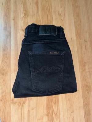 Nudie Jeans - Säljer ett par svarta jeans från Nudie Jeans, Lean Dean. Midja 32cm, längd 91cm. JAG SKICKAR EJ FLER BILDER NÄR JAG BÄR JEANSEN! för bättre inblick i passformen rekommenderar jag att googla på modellnamnet. För storleksguide kolla måtten noggrant då jeansen alltid kan vara uppsydda heller krympta och jag ej tar emot returer :) s5,4