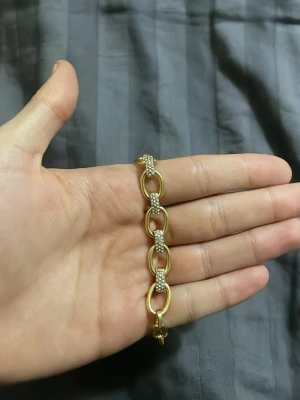 Ingen väst på bilderna - Bilderna visar olika smycken i guldton, bland annat armband och halsband med länkar och detaljer, men ingen väst finns med.