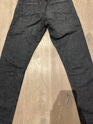 Svarta jeans från Jack & Jones 29/32 - Svarta jeans från Jack & Jones med klassisk femficksdesign och raka ben. Jeansen har diskreta sömmar och är tillverkade i ett robust jeanstyg som passar till många olika stilar. Perfekta för dig som gillar en enkel och stilren look.