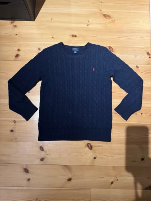 Mörkblå stickad tröja Polo Ralph Lauren - Säljer just nu denna snygga och ÄKTA Kabelstickad mörkblå tröja från Polo Ralph Lauren i storlek XL men sitter som M/S.  är i mycket bra skick  och nypris runt 2000, hör av er vid frågor å funderingar✌️