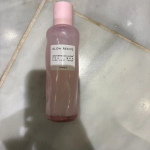 Glow Recipe Watermelon Glow Toner - Glow Recipe Watermelon Glow PHA+BHA Pore-Tight Toner i en snygg rosa plastflaska med skruvlock. Tonern är lätt och fräsch, perfekt för att ge huden en återfuktad och klar känsla. Flaskan har en modern design och rymmer en flytande toner med vattenmelonextrakt.