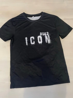Svart ICON t-shirt med tryck - Svart t-shirt från DS02 med coolt vitt tryck där det står 'ICON' på bröstet. Rund hals och korta ärmar. Perfekt för dig som gillar streetstyle och vill sticka ut med ett statement-plagg.
