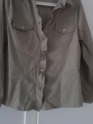 Skjorta med volang  - Skjorta storlek L. Skjortan har volang längs med knapparna.