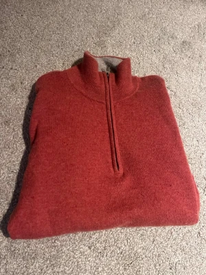 Röd stickad tröja med half zip - Säljer en röd stickad tröja med half zip och hög krage. Perfekt för kyliga dagar och enkel att matcha med jeans eller chinos. Tröjan har en mjuk och skön känsla och passar dig som gillar klassisk stil med en modern twist.