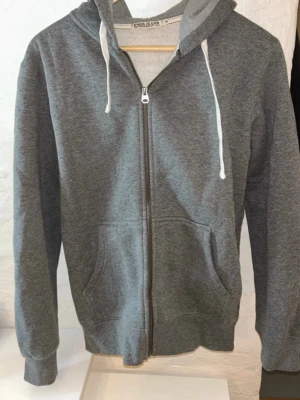 Grå hoodie - Grå hoodie med dragkedja och luva, storlek M. Passar både killar och tjejer. 