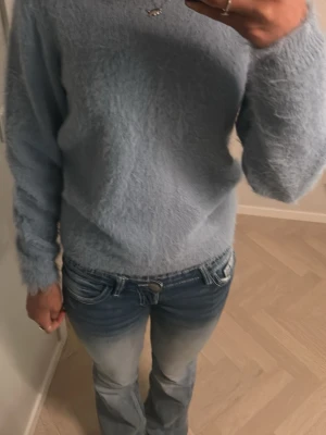 Ljusblå fluffig stickad tröja - Mysig ljusblå stickad tröja med fluffig yta och rund hals. Tröjan har långärmade ärmar. Perfekt att matcha med jeans för en avslappnad stil. Materialet är mjukt och känns skönt mot huden. Köpt från Vinted för nått år sen använt cirka 2 gånger. Storlek xs-s passar säkert mamma också