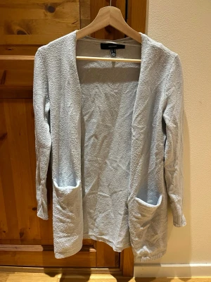 Ljusblå kofta - Ljusblå långärmad kofta i storlek XS från Vero Moda. Väl använd i bra skick. Tyget upplevs nopprigt men då har jag själv använt en noppmaskin som tar bort noppret. Har själv uppfattat plagget som mycket bättre skick efter det. Koftan täcker precis rumpan, den räcker längre desto kortare man är. Säljes då den är för liten. Djur och rökfritt hem.