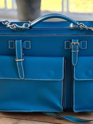 Blå portfölj från Pigga Peggy - Blå väska gjord på italienskt läder, från Pigga Peggy. Observera att väskan har skador på två ställen, dessa påverkar inte användningen dock! Storlek 39x29x11, får plats med laptop mm Originalpris 1350kr, lapp sitter kvar! Hör gärna av er vid funderingar eller förfrågan om ytterligare bilder??