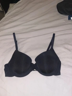 Svart bh - Bilderna visar en svart bh med justerbara axelband och hakknäppning bak, aldrig använd, ingen push up