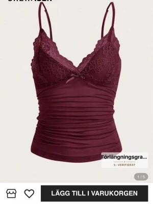 Vinröd spetsdetaljerad linnetopp - Snygg vinröd linnetopp från SHEIN med smala axelband och spetsdetaljer över bysten. Toppen har en v-ringad urringning, blommönstrad spets och en liten rosett framtill. Materialet är mjukt och stretchigt med rynkade partier för en cool look.