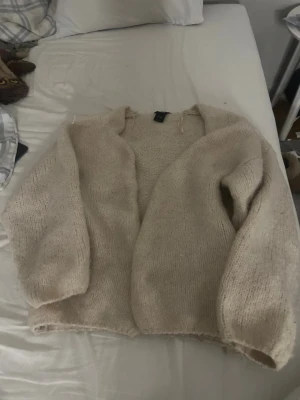 Beige stickad kofta från Lindex - Mysig och fluffig beige stickad kofta från Lindex i storlek XS/S. Koftan har långärmade ärmar och en öppen front utan knappar eller dragkedja. Perfekt att slänga på sig när det är lite kyligt ute. Enkel och stilren design som passar till många olika outfits.