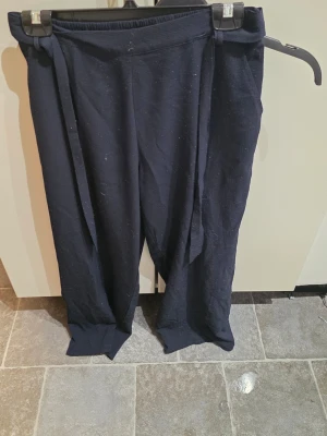 Mörkblå mjukisbyxor från ONLY - Säljer ett par mörkblå mjukisbyxor från ONLY i storlek 38. Byxorna har elastisk midja och snörning för extra komfort. Materialet är mjukt och passar perfekt för chill dagar. Stilen är loose och avslappnad med raka ben.