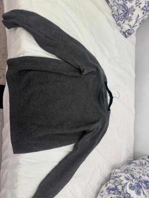 Mörkgrå stickad tröja - Säljer en enkel och stilren mörkgrå stickad tröja med rund hals. Tröjan har långärmade ärmar och är gjord i ett mjukt material som passar perfekt för kyliga dagar. Klassisk modell som är lätt att matcha med jeans eller chinos.