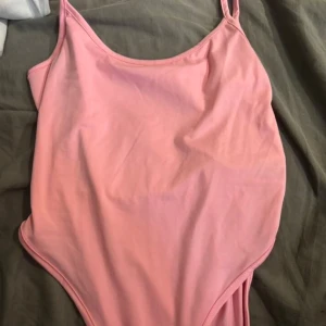 Rosa body med smala axelband - Supersöt rosa body med smala axelband och enkel, stilren design. Materialet är stretchigt och känns mjukt mot huden, perfekt för jeans eller en snygg kjol.