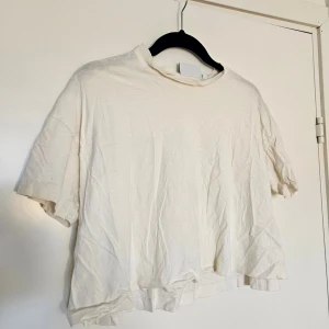 Vit t-shirt från Weekday - Varmvit t-shirt från Weekday med korta ärmar och rund halsringning. Gjord i mjuk bomull. Storlek S. Fint skick