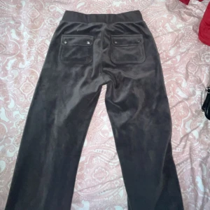 Mörk gråa mjukisbyxor med snörning - Mysiga mörk gråa mjukisbyxor i mjukt material med bred resår i midjan och snörning framtill. Byxorna har stora fickor både fram och bak, samt en diskret logga på ena fickan. Perfekta för chill dagar eller när du vill vara extra bekväm.