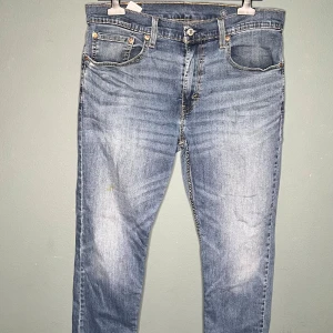Levi's 514 ljusblå jeans W33 L32 - Ljusblå Levi's 514 jeans med klassisk femficksdesign och snyggt slitna detaljer. Jeansen har raka ben och normal passform, tillverkade i mjukt denimtyg. Perfekta för en avslappnad och stilren look.